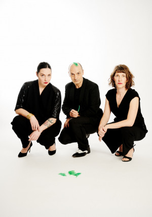 Photo de la pièce Vers l'Oiseau Vert, prise par Anouk Schneider. Trois personnes sont à croupis par terre. Leurs vêtements sont noirs, le fond est blanc. Ils nous regardent.
