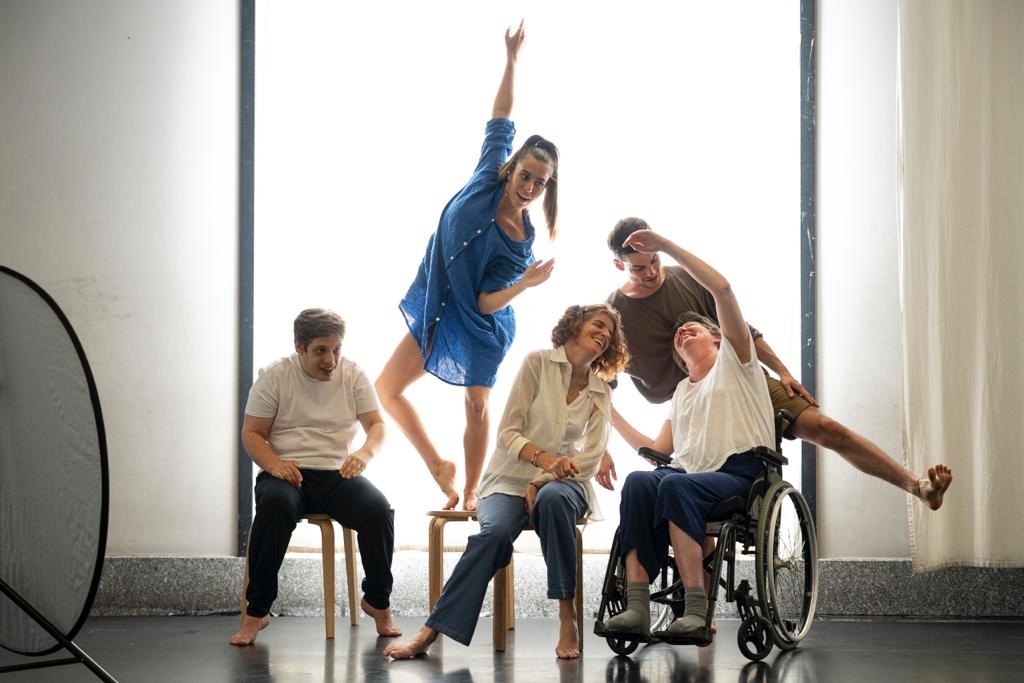 Cette photo a été prise par Manon Weber. Elle représente les artistes du spectacle. On y voit des personnes sur un fauteuil roulant et sur des chaises. Et une personnes est debout derrière sur une chaise.