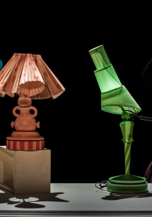 Cinq lampes de couleur différentes sont sur une table. Le comédien et la comédienne sont chacun déguisé en l’une d’elles. Photo de Carlo De Rosa